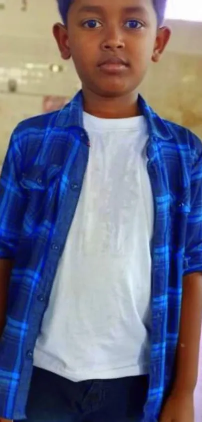 Young boy in a blue checkered shirt standing indoors.