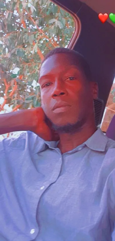 Casual portrait of a man sitting in a car with a scenic tree background.