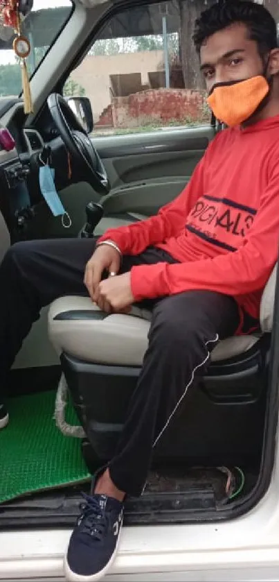 Person in red shirt sitting in a car.