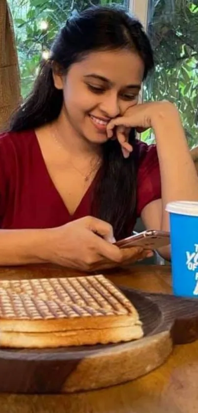 Woman smiling with coffee and sandwich at a table.