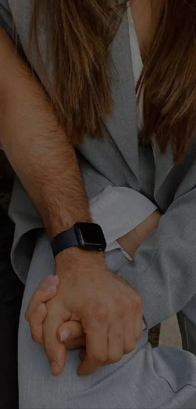 Close-up of intertwined hands in casual attire featuring a black smartwatch.