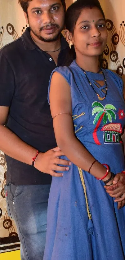 Casual couple standing against patterned background in colorful attire.