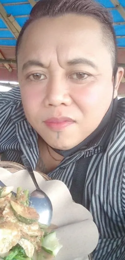 Person enjoying meal under a blue roof.