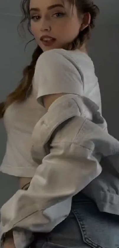 Woman in a stylish jean jacket and white shirt posing gracefully.