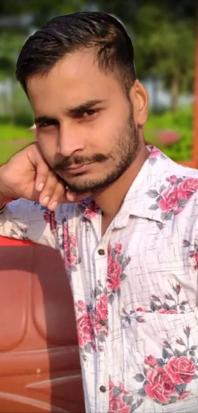 Man in a floral shirt, vibrant nature background.