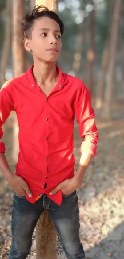 Young man in red shirt standing in forest.