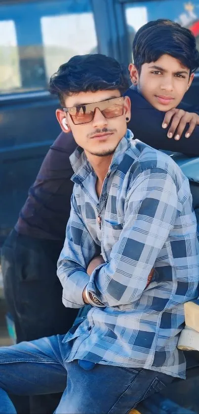 Two friends posing casually by a car.