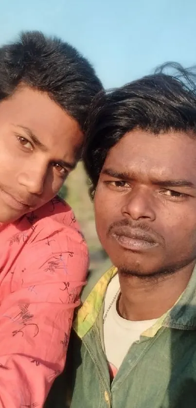 Two friends taking a selfie outdoors on a sunny day.