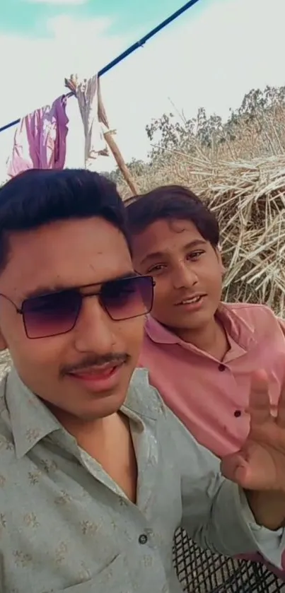 Two friends taking a selfie outdoors with a nature backdrop.