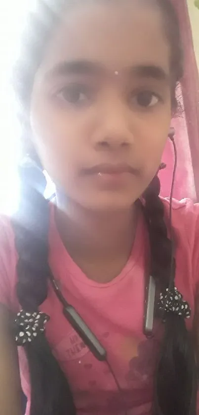 Girl with braids in a pink top, listening to music.