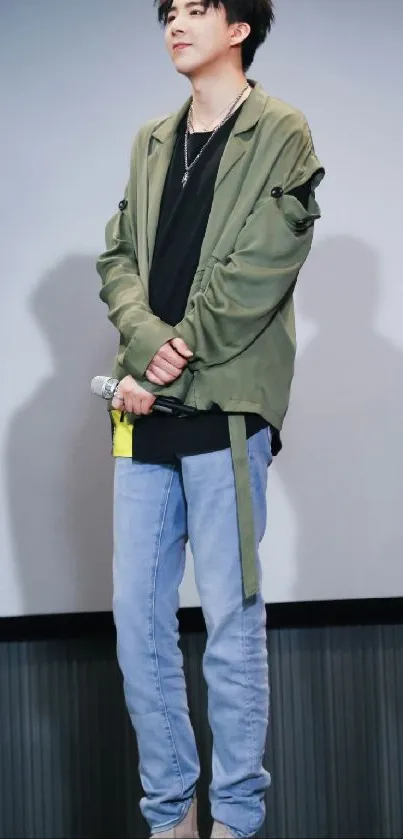 Person in green jacket with microphone and blue jeans.