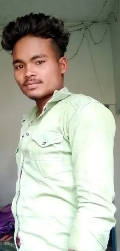 Young man standing indoors wearing a green shirt.