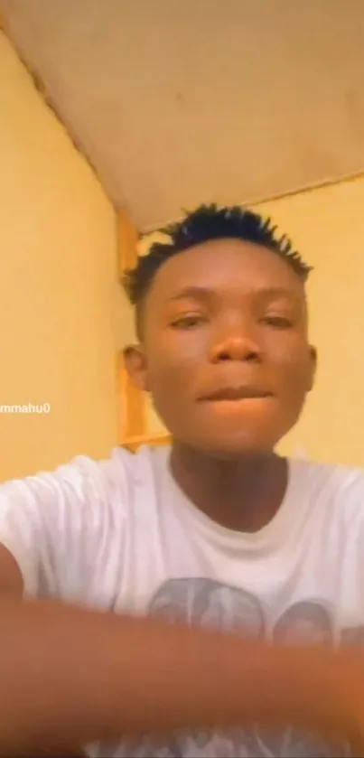 Casual portrait of a young person in a home setting wearing a white t-shirt.