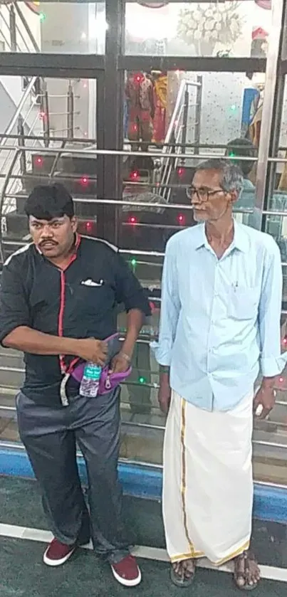 Two men in casual attire at a decorated indoor event.