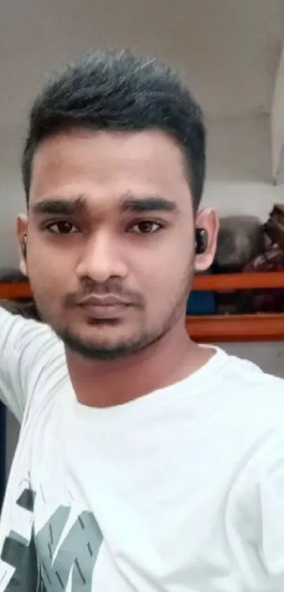 Casual portrait of a young man in a white shirt indoors.