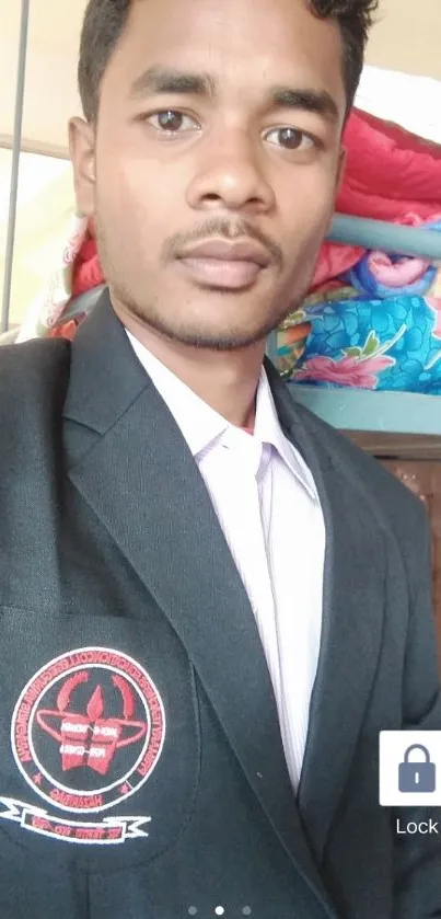 Portrait of a young man in a black blazer indoors with colorful textile background.