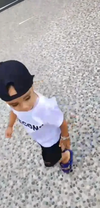 Child in casual summer attire walking on a stone pathway.