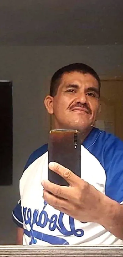 Man taking a casual mirror selfie wearing a blue and white jersey.