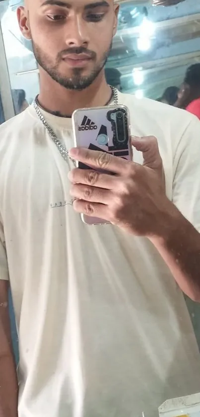 Casual young man taking a mirror selfie in a beige shirt.