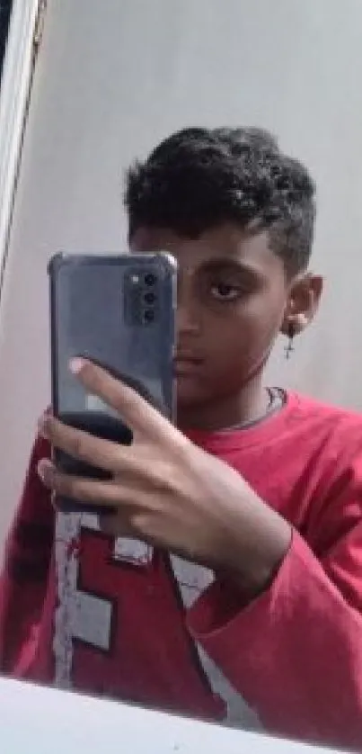 Mirror selfie with smartphone in casual attire.