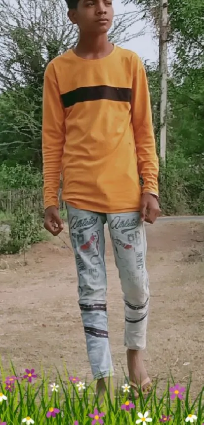 Person in orange top walking in nature with jeans and floral path.