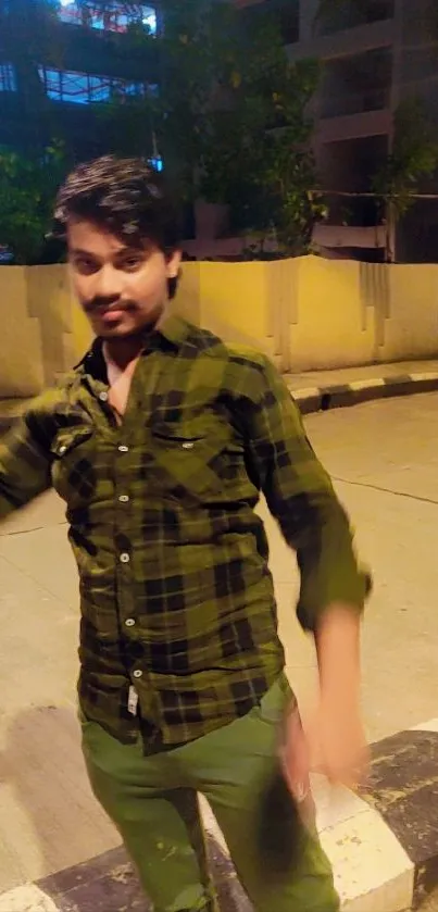 Man stands casually on a night street with warm lighting.