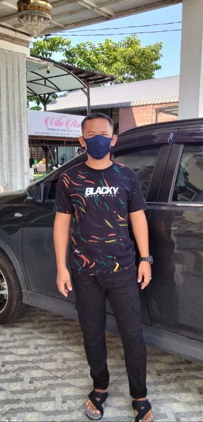 Man with a colorful outfit standing by a car.