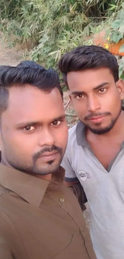 Two friends outdoors with green foliage backdrop.