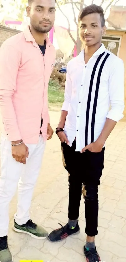 Two friends posing outdoors in casual attire.