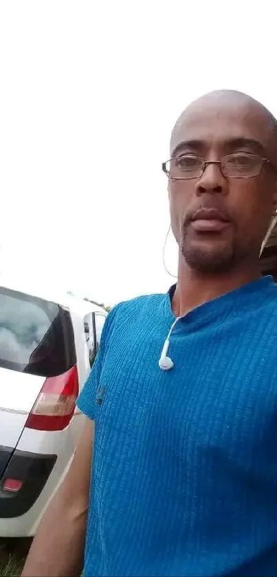 Casual outdoor portrait with blue shirt and white car background.