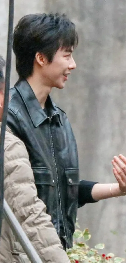 Person in a black leather jacket outdoors, side profile view.