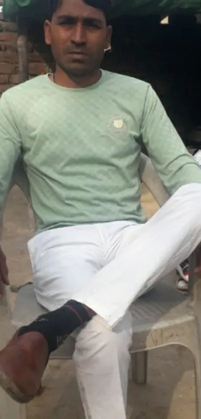 Casual man sitting outdoors in a green shirt.