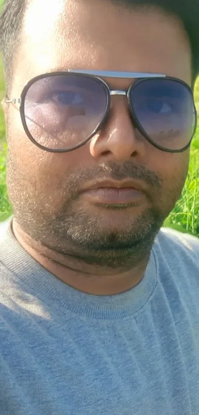 Man in sunglasses with green background and casual attire.