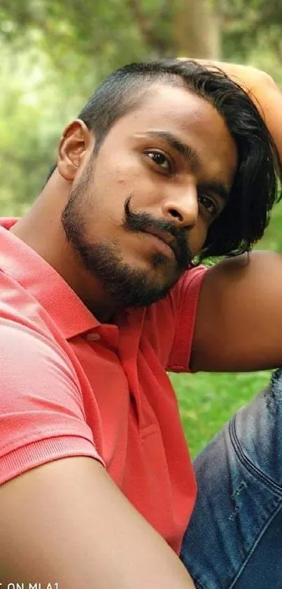 Man in pink shirt relaxing in a lush green garden.