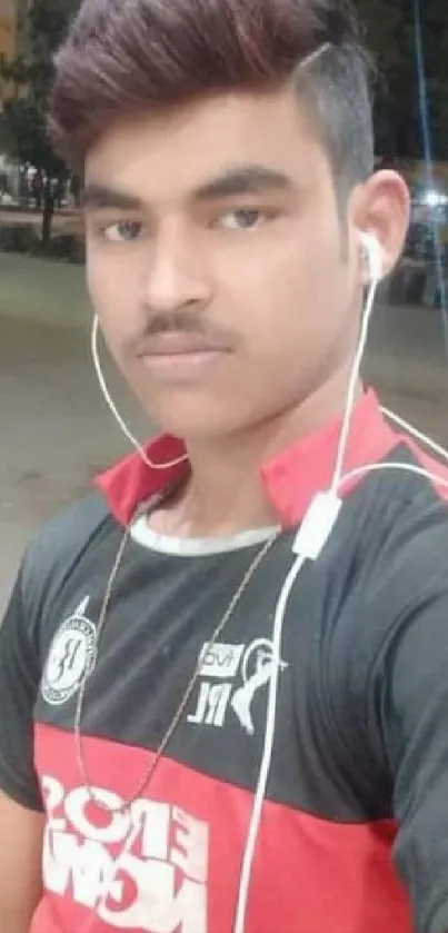 Young man in sporty attire with earphones in an urban outdoor setting.