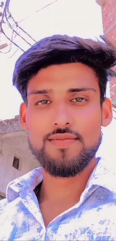 Casual portrait of a bearded man with light blue shirt outdoors.