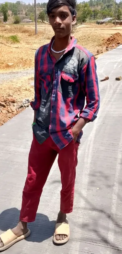 Young man in a checkered shirt and red pants outdoors.