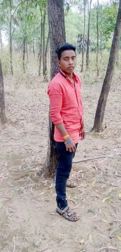 Young man in red shirt standing in a wooded area for a casual portrait.