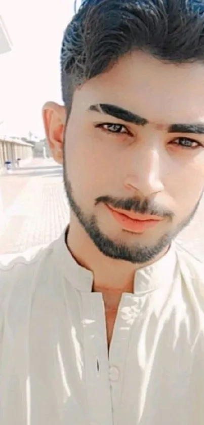 Young man posing outdoors in casual attire, with natural light.