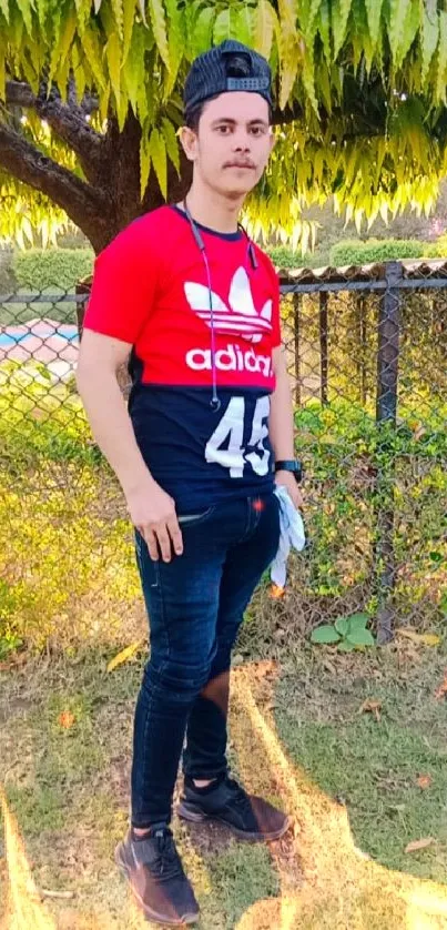 Young man in red shirt outdoors with green background.