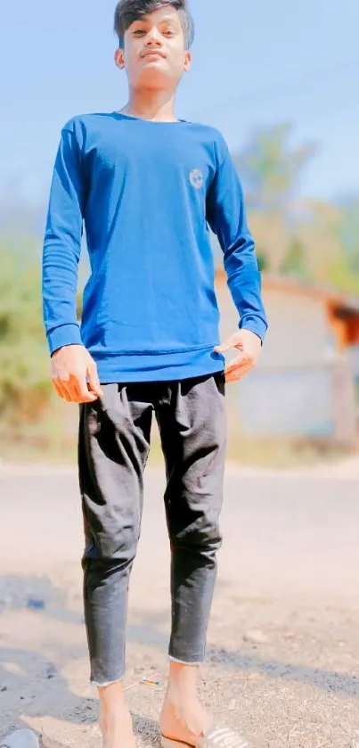 Person in a blue shirt standing outdoors with a casual pose.