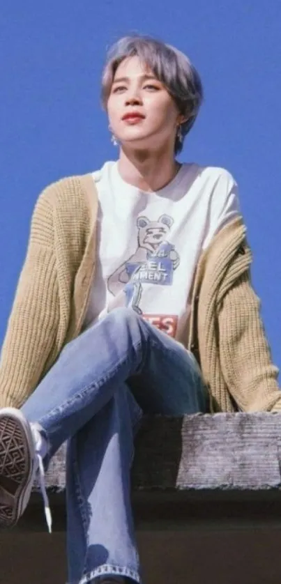 Stylish person sitting under a clear blue sky in casual attire.