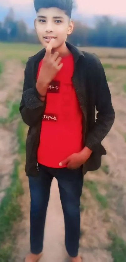 A young person posing outdoors in a casual red and black outfit.