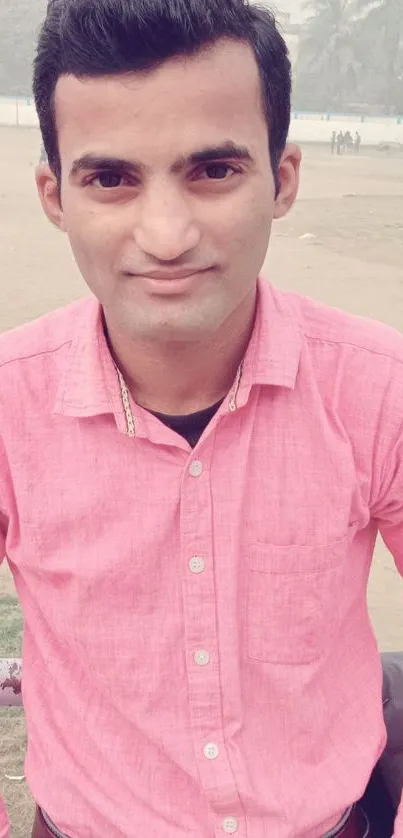 Man in pink shirt outdoors with a casual look.