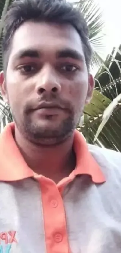 Casual portrait of a man outdoors with palm leaves.