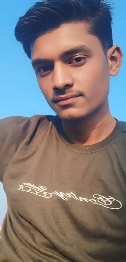 Young person taking a selfie outdoors, set against a blue sky.