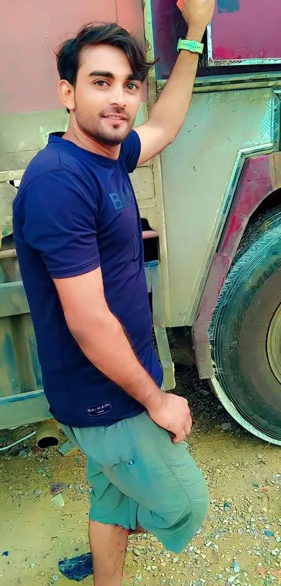 Man in casual attire leaning on an old truck.