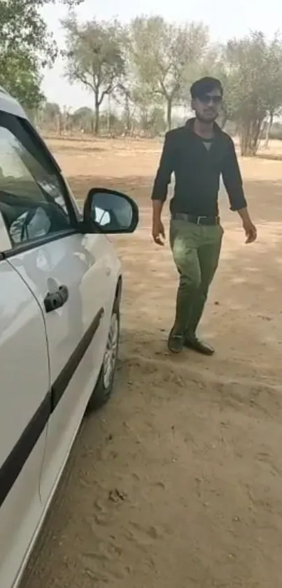 Person in casual attire with car in desert setting.