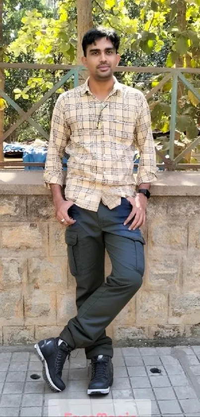 Man in casual attire outdoors with green background.