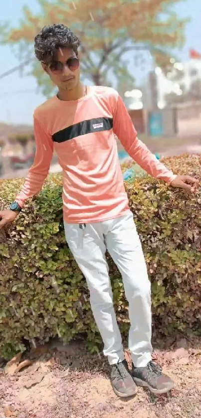 Man in casual attire posing in park setting.